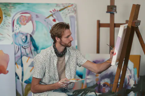 Künstlerin malt mit Farbpalette in der Hand auf einer Leinwand