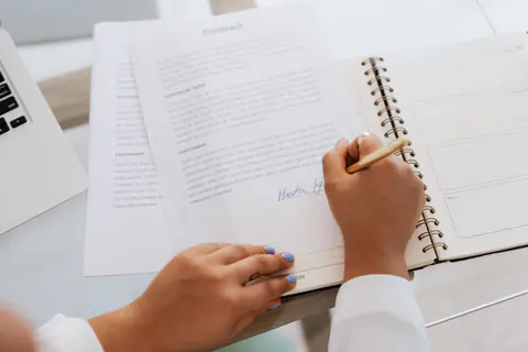 Hände unterschreiben einen Vertrag auf einem Schreibtisch