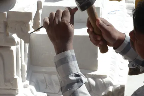 Bildhauer bearbeitet eine Steinskulptur mit Hammer und Meißel